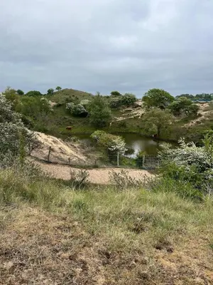 a hill with a body of water in a field at Ons Bijhuis in Wijk aan Zee