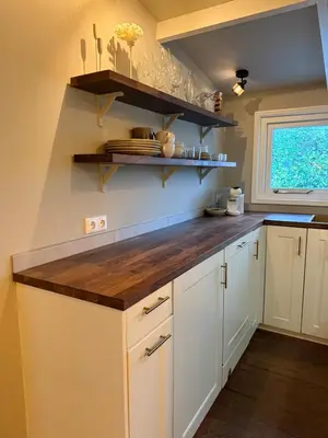 a kitchen with white cabinets and a wooden counter top at White cottage on the Vecht! Beautiful surroundings in Nieuwersluis