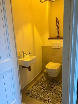 a yellow bathroom with a sink and a toilet at White cottage on the Vecht! Beautiful surroundings in Nieuwersluis