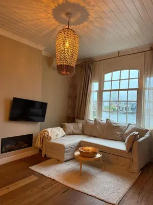 a living room with a couch and a chandelier at White cottage on the Vecht! Beautiful surroundings in Nieuwersluis