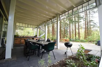 a screened in porch with a table and chairs at Klein Nieuwe Wegen in Ons Belang