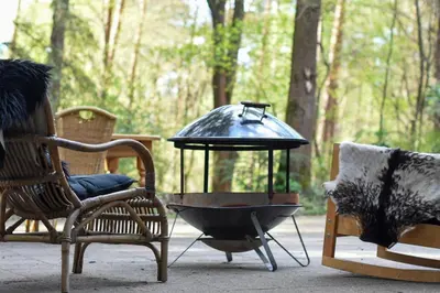 a grill sitting on a patio with two chairs and a table at Klein Nieuwe Wegen in Ons Belang