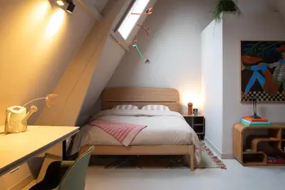 a bedroom with a bed with a desk and a window at The Painters Loft sleeping among the art in Haarlem