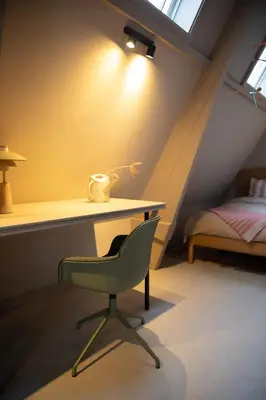 a desk and a chair in a room with a bed at The Painters Loft sleeping among the art in Haarlem