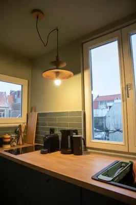 a kitchen with a counter and two windows at The Painters Loft sleeping among the art in Haarlem