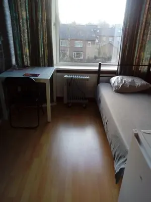 a bedroom with a bed and a desk and a window at Short stay in Weesp