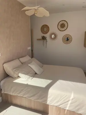 a bed with white sheets and a ceiling fan at Knusse kamer met zonnig terrasje in Zandvoort