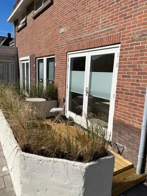 a brick building with windows and plants in front of it at Knusse kamer met zonnig terrasje in Zandvoort