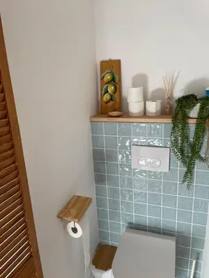 a bathroom with a toilet and a blue tiled wall at Knusse kamer met zonnig terrasje in Zandvoort