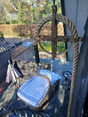 a wooden swing with a wheel in a yard at Fuchsiahoeve in Blaricum