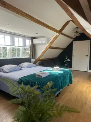 a bedroom with a bed with a green blanket at Fuchsiahoeve in Blaricum