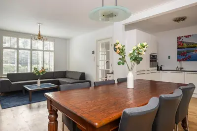 a kitchen and living room with a wooden table and chairs at Lovely House in Zeist