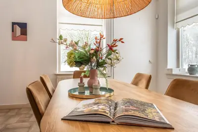 a dining room table with a book and a vase at Private Estate Villa near Amsterdam with Hottub 12p in Abcoude