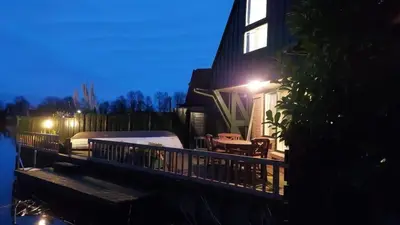 a house with a wooden deck with a table and a patio at Ferienwohnung Nordholland in Nieuwe-Niedorp