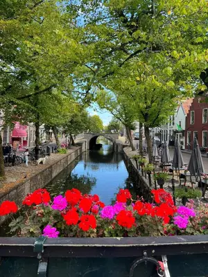 a canal with flowers and a bridge in a city at Ferienwohnung Nordholland in Nieuwe-Niedorp