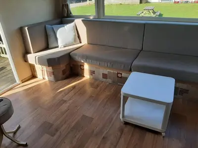 a living room with a couch and a stool at Arizonahaus Holland Nähe Meer in Dirkshorn