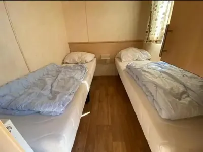 two beds in a small room with wooden floors at Arizonahaus Holland Nähe Meer in Dirkshorn