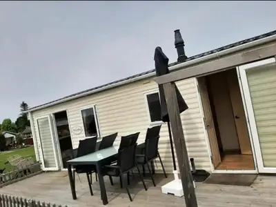 a table and chairs on a deck with a house at Arizonahaus Holland Nähe Meer in Dirkshorn