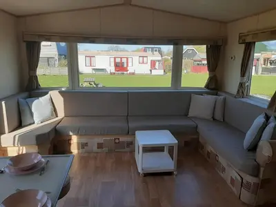 a living room with a couch and a table at Arizonahaus Holland Nähe Meer in Dirkshorn