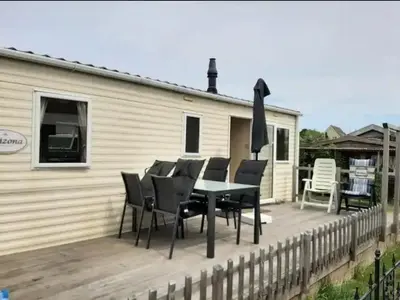 a patio with a table and chairs on a deck at Arizonahaus Holland Nähe Meer in Dirkshorn