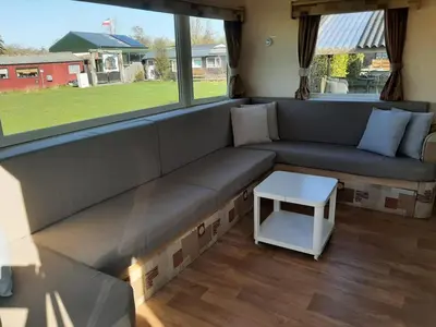 a living room with a couch and a table at Arizonahaus Holland Nähe Meer in Dirkshorn