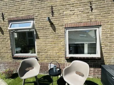 two chairs and a lamp in front of a brick building at Holiday Home Tiny House QuDi by Interhome in Noordwijk