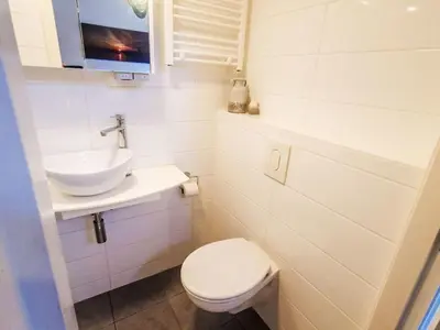 a white bathroom with a sink and a toilet at Holiday Home De Bosuil by Interhome in Noordwijk aan Zee