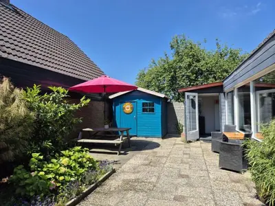 a blue shed with a picnic table and a red umbrella at Holiday Home Sunset by Interhome in Noordwijkerhout