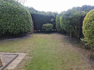a garden with a hedge and a grass yard at Holiday Home Zeelust by Interhome in Noordwijkerhout