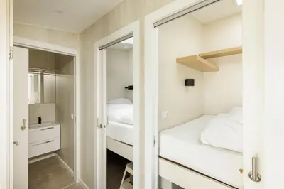 a small bedroom with two beds and a mirror at Cabana's direct op het strand in Zandvoort