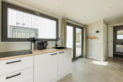 a kitchen with white cabinets and a large window at Cabana's direct op het strand in Zandvoort