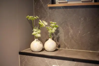 two white vases sitting on a shelf with flowers at De Tuinfluiter 7 in Noordwijk aan Zee