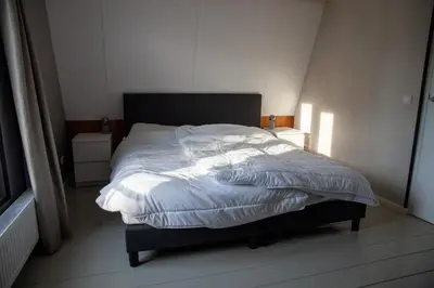 a bedroom with a bed with white sheets at De Tuinfluiter 7 in Noordwijk aan Zee