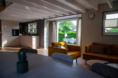 a living room with a table and chairs and a kitchen at De Tuinfluiter 7 in Noordwijk aan Zee