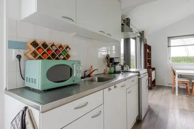 a kitchen with a sink and a microwave on a counter at Huisje aan het einde - 273 in Warmenhuizen