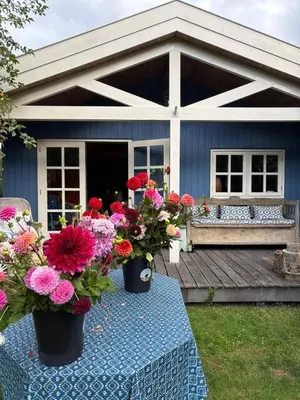 two vases of flowers on a table in front of a house at Houten familiehuisje Noordwijk met grote tuin in Noordwijk aan Zee