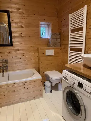 a bathroom with a tub and a toilet and a washing machine at Houten familiehuisje Noordwijk met grote tuin in Noordwijk aan Zee