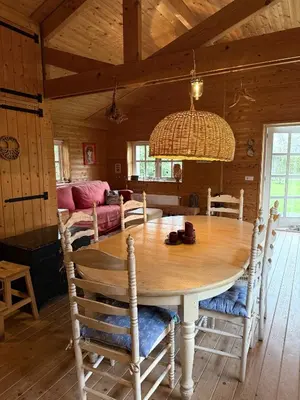 a dining room with a wooden table and chairs at Houten familiehuisje Noordwijk met grote tuin in Noordwijk aan Zee