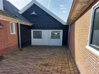 a garage with a white door and a brick wall at Dirkshorn Holiday Home for 4 in Dirkshorn