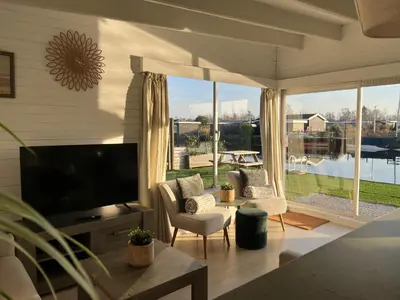 a living room with a tv and a large window at Chalet Kievietsbuurt Roeleveld Estate in Breukelen