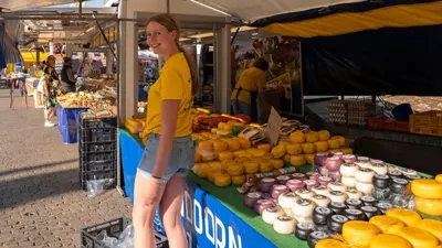 a woman standing in front of a fruit stand at a market at Studio De Gravin in Gouda