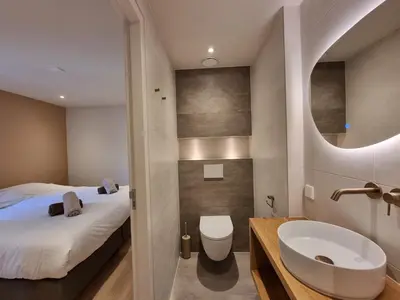 a bathroom with a bed and a sink and a toilet at LÖYLY Egmond in Egmond aan Zee