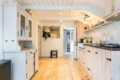 a kitchen with white cabinets and a wooden floor at farmhouse in Wijdewormer