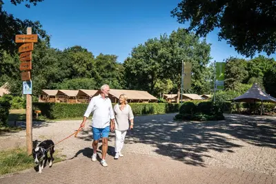 a man and woman walking a dog on a leash at Buytenplaats Gooise Heide in Huizen