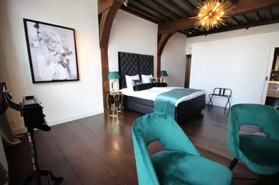 a bedroom with a bed and chairs in a room at Boutique Hotel Steenhof Suites - Adults Only in Leiden