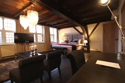 a room with a bed and a table and chairs at Boutique Hotel Steenhof Suites - Adults Only in Leiden