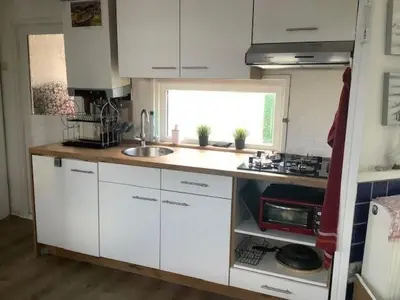 a small kitchen with white cabinets and a sink at Apartment Chalet Meise by Interhome in Wervershoof