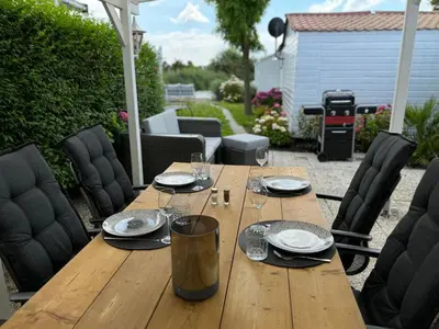 a wooden table with plates and wine glasses on a patio at Holiday Home in Wervershoof mit Terrasse und Garten by Interhome in Wervershoof