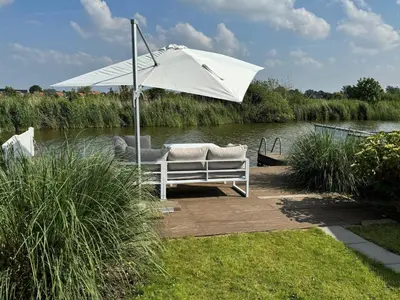 a white umbrella sitting on a dock next to a river at Holiday Home in Wervershoof mit Terrasse und Garten by Interhome in Wervershoof