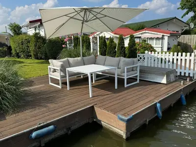 a table and chairs on a wooden deck with an umbrella at Holiday Home in Wervershoof mit Terrasse und Garten by Interhome in Wervershoof